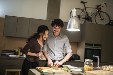 Ehepaar schneidet Gemüse und kocht Abendessen in der Wohnküche - CAIF22690