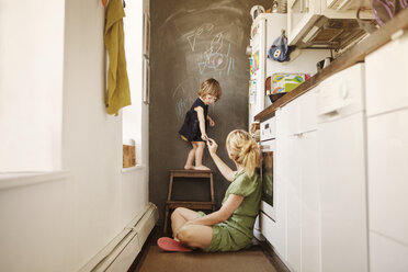 Mother giving chalk to daughter at home - CAVF61050