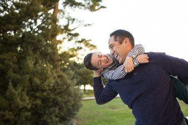 Glücklicher Vater, der mit seinem Sohn spielt, während er im Park bei Sonnenuntergang vor dem klaren Himmel steht - CAVF61060