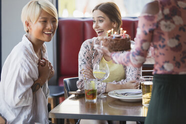 Aufgeregte junge Frauen Freunde feiern Geburtstag mit Kuchen im Restaurant - CAIF22705