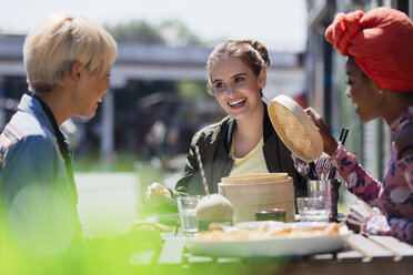 Junge Frauen, die in einem sonnigen Straßencafé Dim Sum zu Mittag essen - CAIF22728