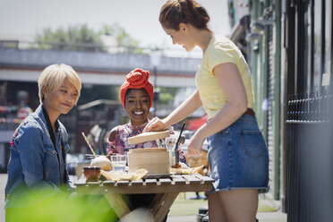 Junge Freundinnen genießen ein Dim Sum-Mittagessen in einem sonnigen Straßencafé - CAIF22730