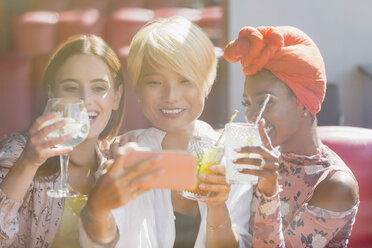 Junge Frauen Freunde trinken Cocktails und nehmen Selfie mit Smartphone in sonnigen Bar - CAIF22737