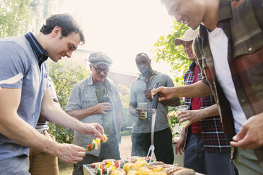 Männliche Freunde stehen um einen Grill im Hinterhof - CAIF22742