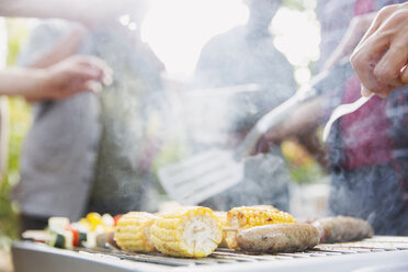 Corncobs, sausages and vegetable skewers cooking on barbecue grill - CAIF22743