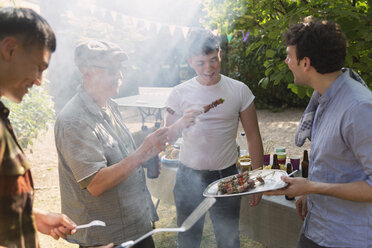 Male friends enjoying barbecue in backyard - CAIF22744