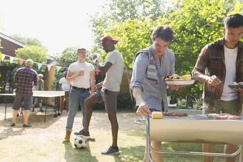 Männliche Freunde beim Grillen im sonnigen Sommergarten - CAIF22752