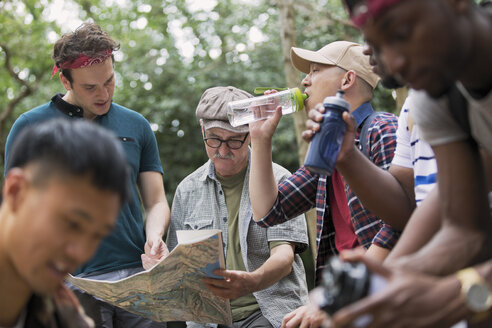 Männergruppe mit Karte und Wasserflaschen beim Wandern im Wald - CAIF22757