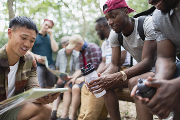 Men friends looking at hiking map in woods - CAIF22761