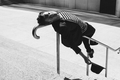 Porträt eines jungen Mannes, der sich an ein städtisches Geländer lehnt, lizenzfreies Stockfoto