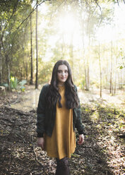 Porträt eines Mädchens mit langen Haaren, das vor einem Baum im Wald steht - CAVF61073