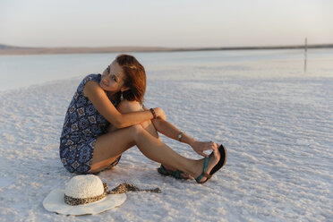 Porträt einer Frau mit Hut, die auf einer Saline sitzt, gegen einen klaren Himmel bei Sonnenuntergang - CAVF61115