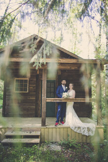 Porträt eines frisch vermählten Paares auf einer Veranda im Wald - CAVF61119