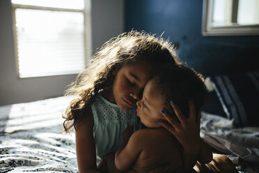 Schwester mit geschlossenen Augen umarmt niedlich shirtless Bruder beim Entspannen auf dem Bett zu Hause - CAVF61129