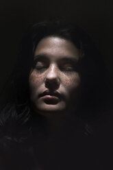 Close-up of teenage girl with eyes closed against black background - CAVF61145