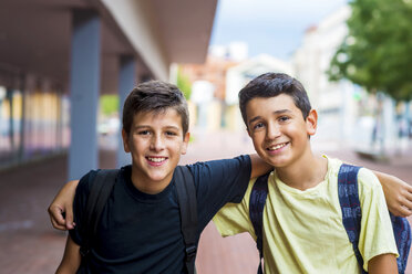 Portrait of smiling friends with arms around standing on footpath - CAVF61149