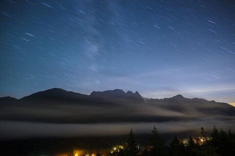 Scenic view of mountains against star trails at night stock photo