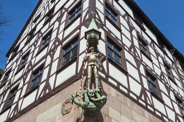 Germany, Nuremberg, Golden statue on a half timbered house in the medieval town center - RUNF01377