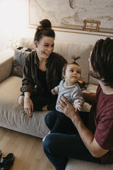 Glückliche Familie mit Baby-Mädchen im Wohnzimmer zu Hause - LHPF00447