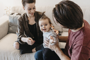 Glückliche Familie mit Baby-Mädchen im Wohnzimmer zu Hause - LHPF00448