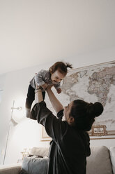 Glückliche Mutter spielt mit Baby Mädchen im Wohnzimmer zu Hause - LHPF00453