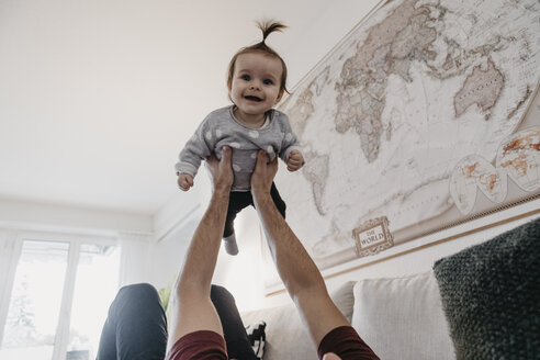 Glückliches kleines Mädchen, das von ihrem Vater im Wohnzimmer hochgehoben wird - LHPF00455