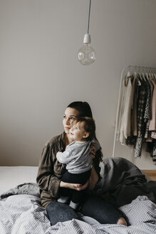 Mother with baby girl sitting on bed at home - LHPF00464