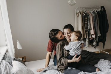 Glückliche Familie mit einem kleinen Mädchen, das zu Hause auf dem Bett sitzt - LHPF00466