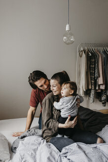 Glückliche Familie mit einem kleinen Mädchen, das zu Hause auf dem Bett sitzt - LHPF00467