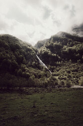 Landschaftlicher Blick auf einen Wasserfall inmitten von Bäumen auf einem Berg vor bewölktem Himmel - CAVF61239
