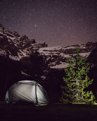 Beleuchtetes Zelt auf einem Feld am Berg gegen ein Sternenfeld bei Nacht - CAVF61244