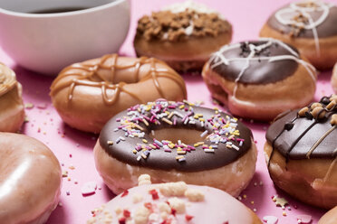 Hohe Winkel Ansicht der verschiedenen Donuts mit Kaffee auf rosa Hintergrund angeordnet - CAVF61302