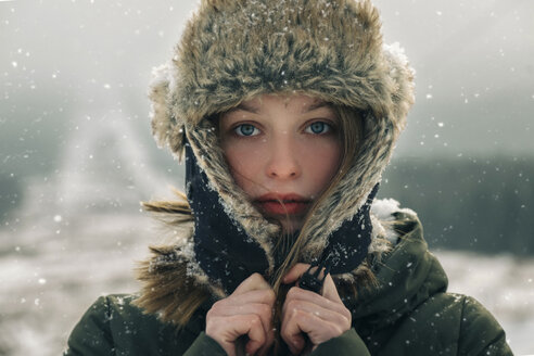 Nahaufnahme einer Frau in warmer Kleidung, die bei Schneefall im Freien steht - CAVF61312