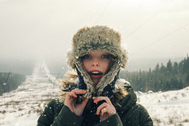 Porträt einer Frau in warmer Kleidung auf einem Berg stehend gegen den Himmel bei Schneefall - CAVF61314