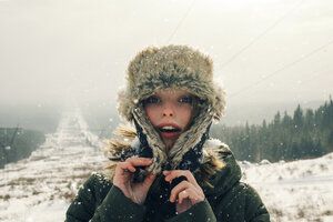 Portrait of woman in warm clothing standing on mountain against sky during snowfall - CAVF61314