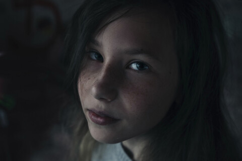 Nahaufnahme eines Mädchens, das zu Hause in der Dunkelkammer sitzt, lizenzfreies Stockfoto