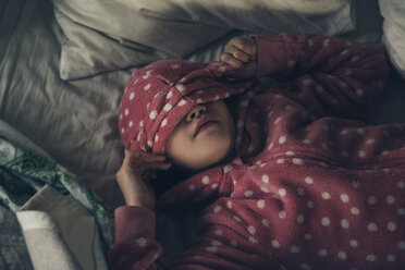 Hohe Winkel Ansicht des Mädchens trägt rosa Kapuzenjacke, während auf dem Bett zu Hause liegen - CAVF61319