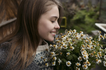 Nahaufnahme einer glücklichen Frau, die einen Blumenstrauß hält, während sie im Freien steht - CAVF61330
