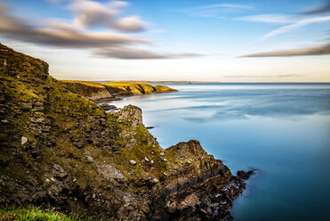 Scenic view of blue sea by hill against sky during sunset - CAVF61362