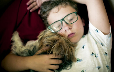Hochformatige Ansicht eines Jungen mit Yorkshire Terrier, der zu Hause schläft - CAVF61398