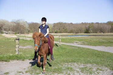 Frau reitet auf einem Feld an einem sonnigen Tag - CAVF61424