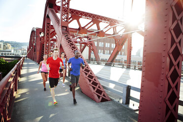 Athletenfreunde laufen auf einer Fußgängerbrücke in der Stadt an einem sonnigen Tag - CAVF61518