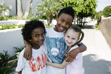 Portrait of smiling siblings standing on footpath in city - CAVF61542