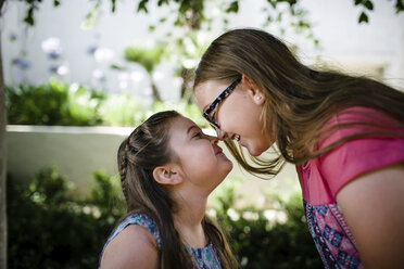 Side view of playful sisters rubbing noses at park - CAVF61553