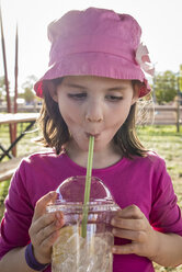 Nettes Mädchen trinkt ein kaltes Getränk, während sie auf einem Feld steht - CAVF61564