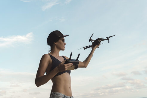 Frau hält Drohne unter Himmel mit Wolken - KNTF02708