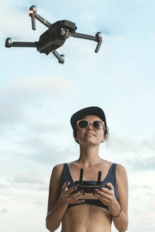 Frau fliegt Drohne unter Himmel mit Wolken - KNTF02712