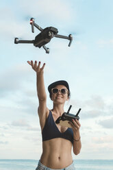 Indonesien, Bali, Nusa Dua, Frau fliegt Drohne am Strand - KNTF02713