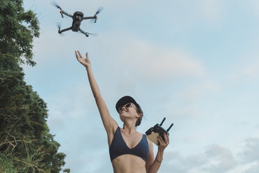 Indonesien, Bali, Nusa Dua, Frau fliegt Drohne am Strand - KNTF02715