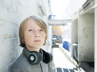 Nahaufnahme eines Jungen mit Kopfhörern, der an einer Wand steht - CAVF61599